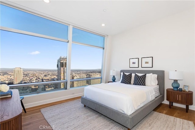 bedroom with baseboards, wood finished floors, and recessed lighting