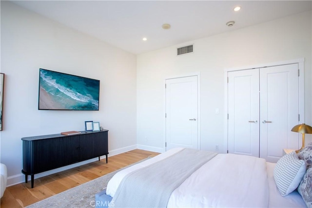 bedroom featuring wood finished floors, a closet, baseboards, visible vents, and recessed lighting