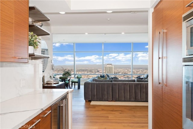 kitchen with light wood-type flooring, modern cabinets, brown cabinets, open shelves, and beverage cooler