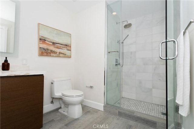 full bath featuring toilet, baseboards, vanity, and a stall shower