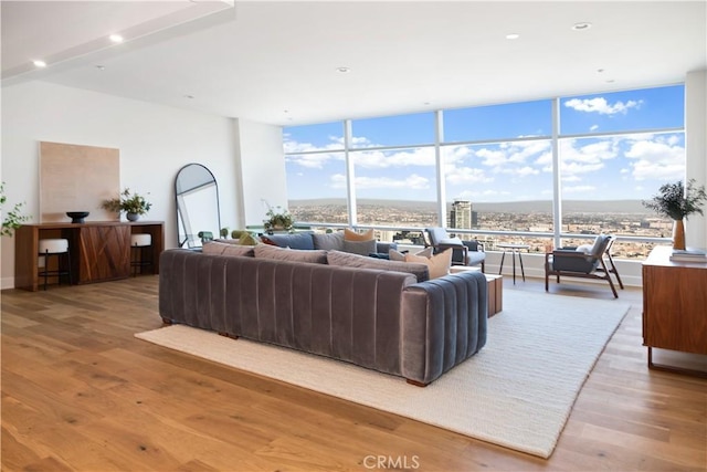 living area with recessed lighting, wood finished floors, plenty of natural light, and a wall of windows