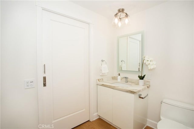 half bathroom featuring toilet, vanity, and wood finished floors