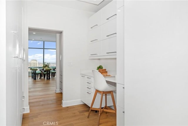office space with built in desk, light wood-style flooring, and baseboards