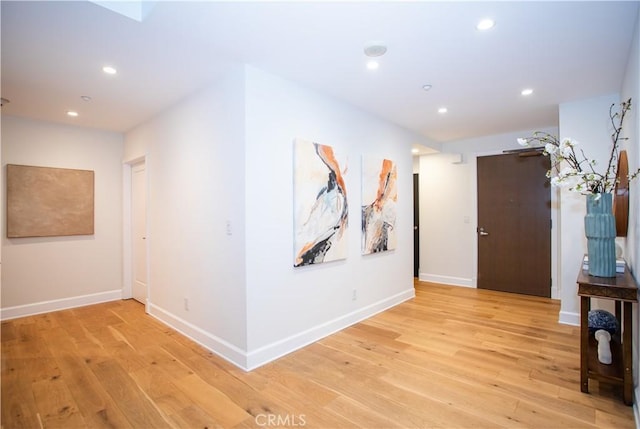corridor featuring baseboards, light wood-style floors, and recessed lighting