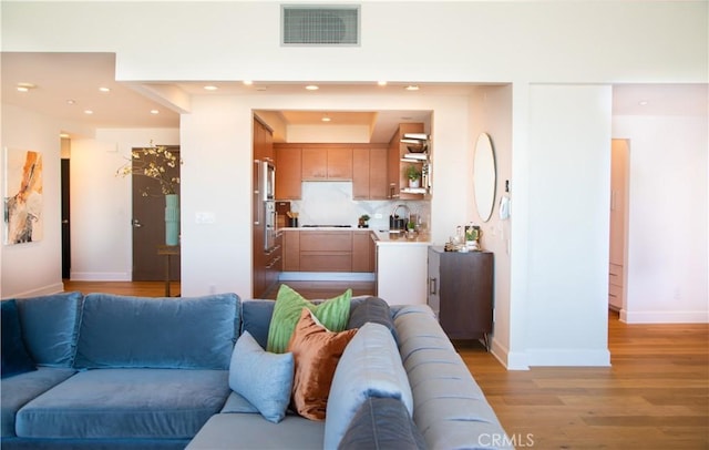 living area featuring baseboards, light wood-style floors, visible vents, and recessed lighting