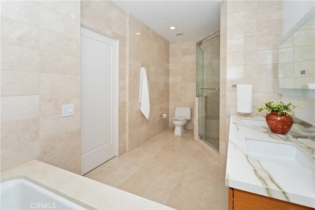 bathroom featuring a shower stall, tile walls, double vanity, toilet, and tile patterned flooring