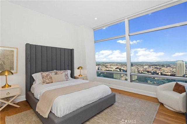 bedroom featuring a view of city and wood finished floors