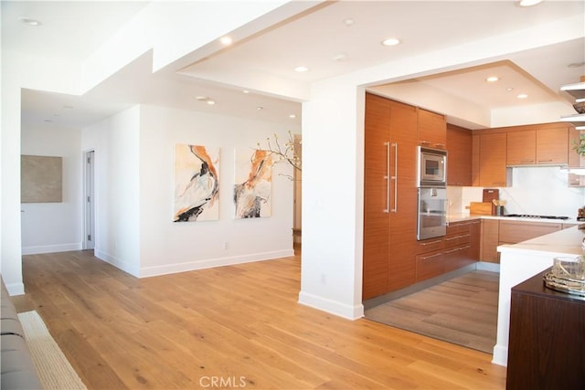 kitchen featuring brown cabinets, stainless steel appliances, light wood finished floors, and recessed lighting
