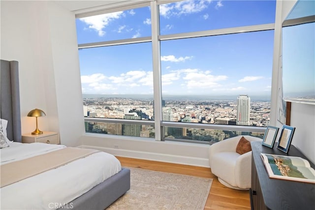 bedroom featuring a view of city, multiple windows, and wood finished floors