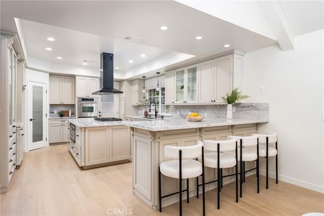 kitchen featuring sink, island range hood, a center island, appliances with stainless steel finishes, and kitchen peninsula