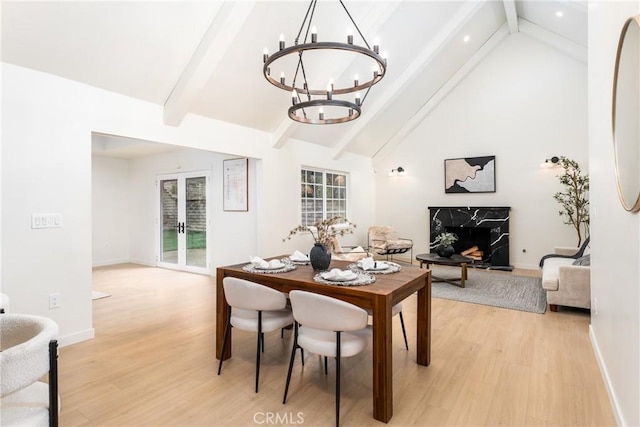 dining area featuring high vaulted ceiling, a notable chandelier, light hardwood / wood-style floors, beam ceiling, and french doors