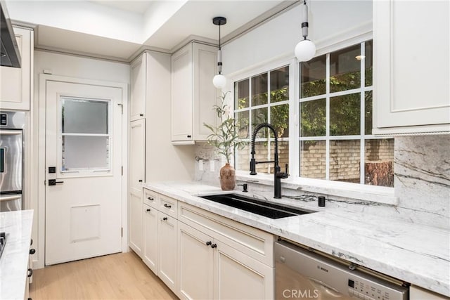 kitchen with sink, light stone counters, decorative light fixtures, stainless steel appliances, and decorative backsplash