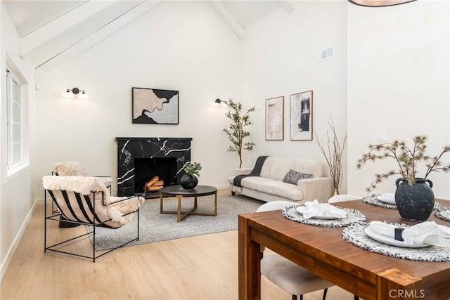 living room with beam ceiling, wood-type flooring, high vaulted ceiling, and a fireplace