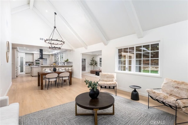 living room featuring high vaulted ceiling, light wood-type flooring, a chandelier, and beam ceiling