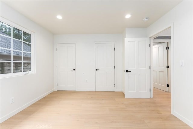 unfurnished bedroom featuring multiple closets and light hardwood / wood-style floors