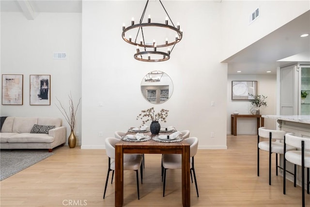 dining space with a towering ceiling, an inviting chandelier, and light hardwood / wood-style floors