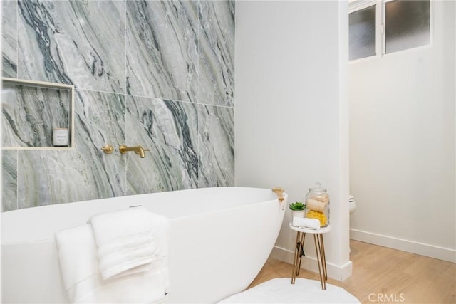 bathroom featuring a washtub, wood-type flooring, and toilet