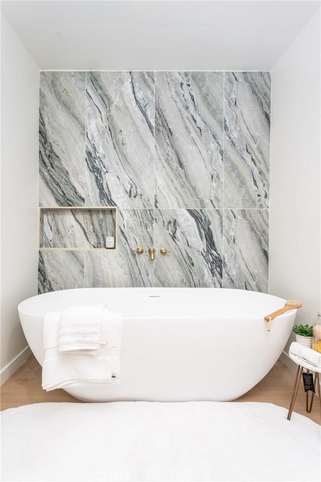 bathroom featuring wood-type flooring and a bath