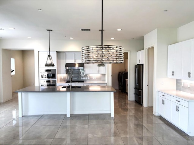 kitchen with white cabinetry, decorative light fixtures, a kitchen island with sink, and black fridge