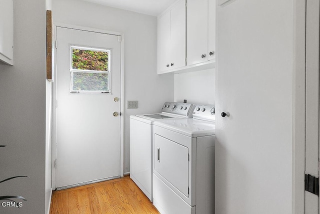 laundry area featuring separate washer and dryer, light hardwood / wood-style flooring, and cabinets