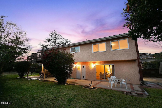 back house at dusk with a yard and a patio area