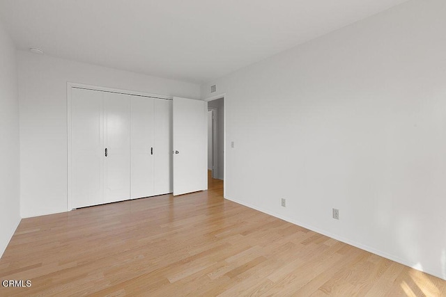 unfurnished bedroom featuring light hardwood / wood-style flooring and a closet