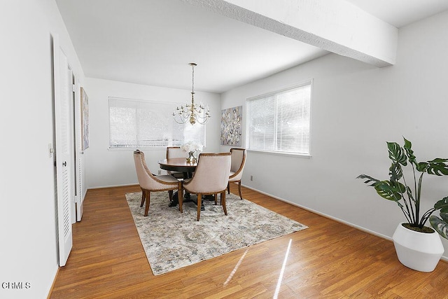 dining space with hardwood / wood-style flooring and a notable chandelier