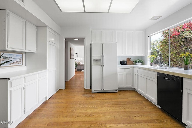 kitchen featuring sink, black dishwasher, white fridge with ice dispenser, white cabinets, and light wood-type flooring