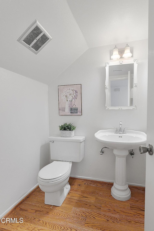 bathroom featuring hardwood / wood-style flooring, lofted ceiling, and toilet