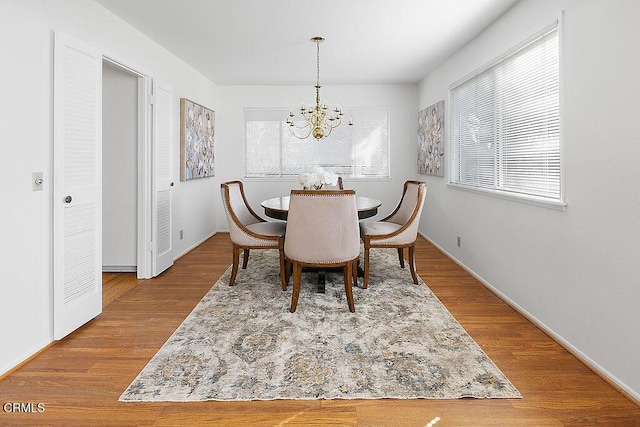 dining area with hardwood / wood-style floors and an inviting chandelier