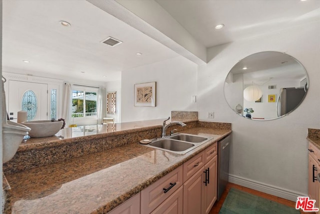 kitchen with light brown cabinetry, sink, dishwasher, and stone counters