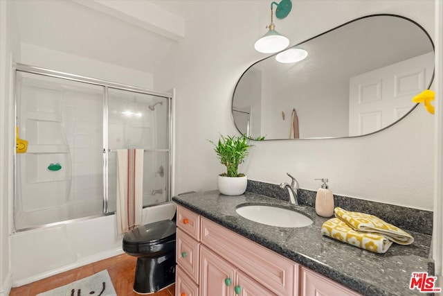 full bathroom featuring enclosed tub / shower combo, vanity, tile patterned floors, and toilet