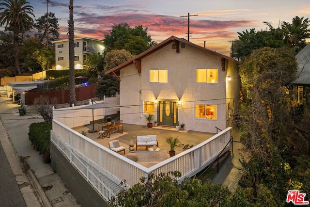 back house at dusk featuring an outdoor living space and a patio