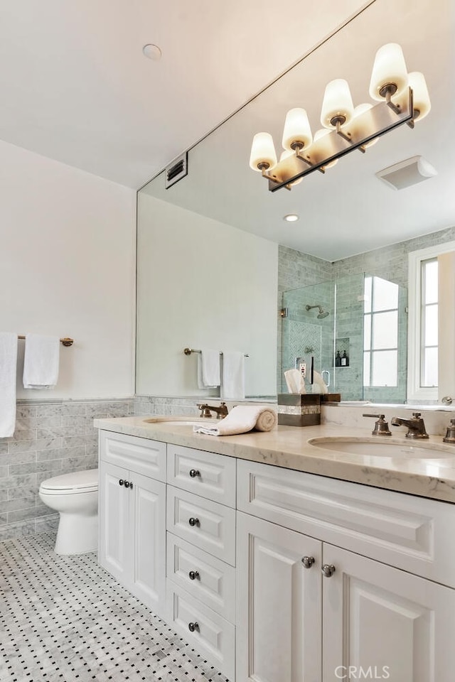 bathroom featuring walk in shower, vanity, toilet, and tile walls