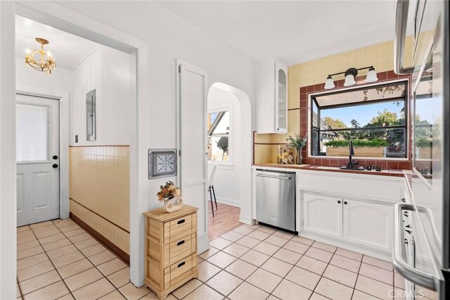 kitchen featuring dishwasher, sink, white cabinets, hanging light fixtures, and fridge