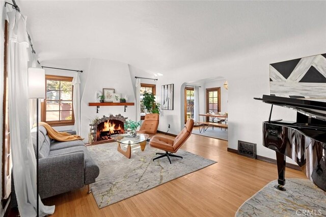 living room with hardwood / wood-style floors, vaulted ceiling, and a large fireplace