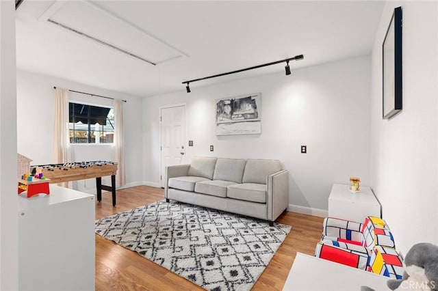 living area featuring light wood-style floors, rail lighting, and baseboards