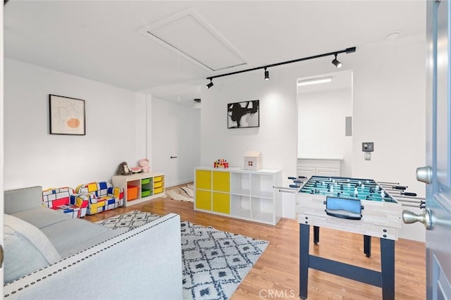 game room with attic access, track lighting, and wood finished floors