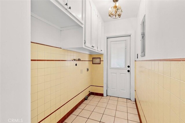 doorway to outside featuring tile walls, a chandelier, and light tile patterned floors