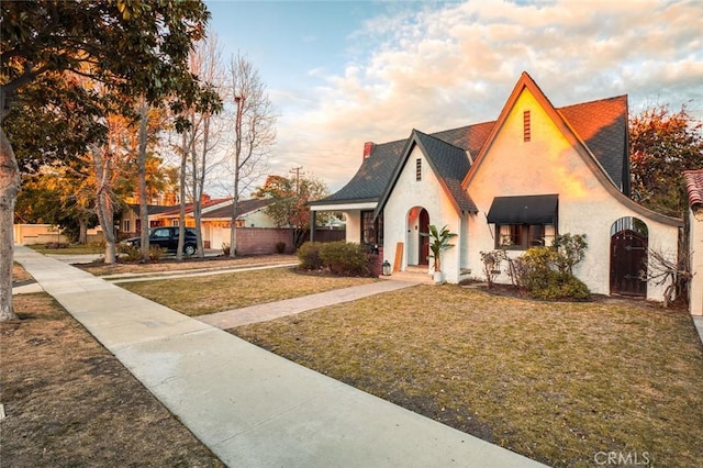 tudor home featuring a front lawn and stucco siding