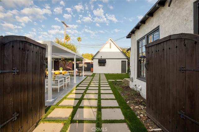 view of patio with an outdoor structure, fence, and a gate