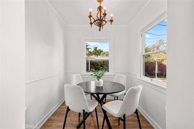 dining area with ornamental molding, a chandelier, wood-type flooring, and plenty of natural light