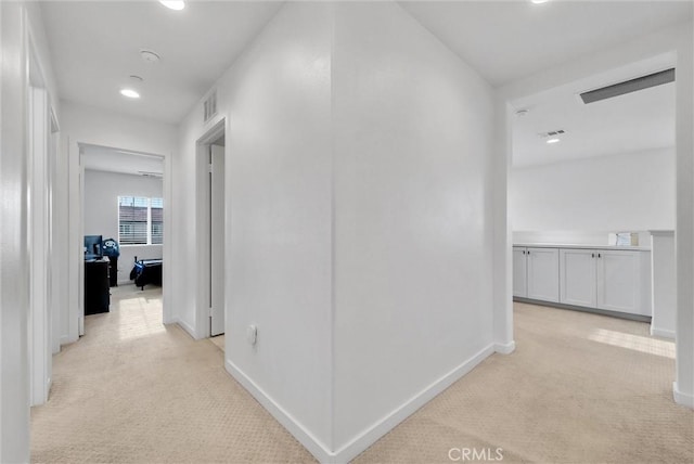 corridor with light carpet, baseboards, and visible vents