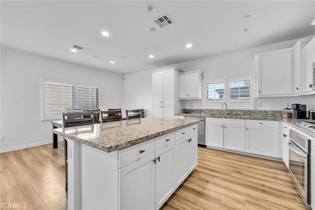 kitchen featuring light stone counters, appliances with stainless steel finishes, a center island, and white cabinets