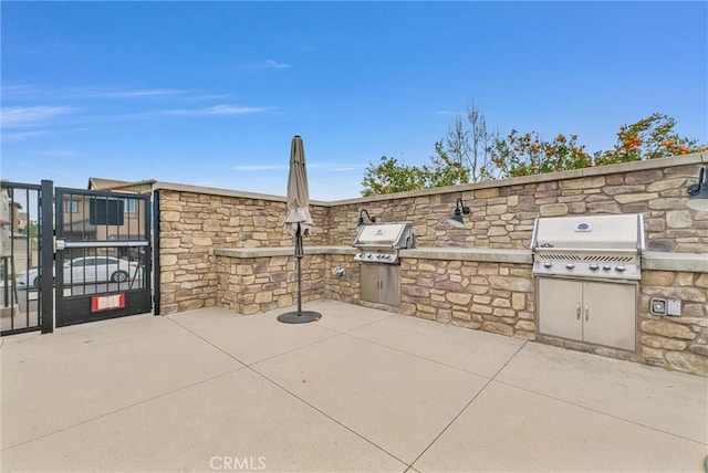 view of patio / terrace featuring a gate, an outdoor kitchen, and area for grilling