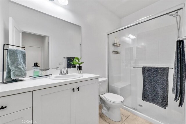 bathroom with tile patterned flooring, vanity, an enclosed shower, and toilet