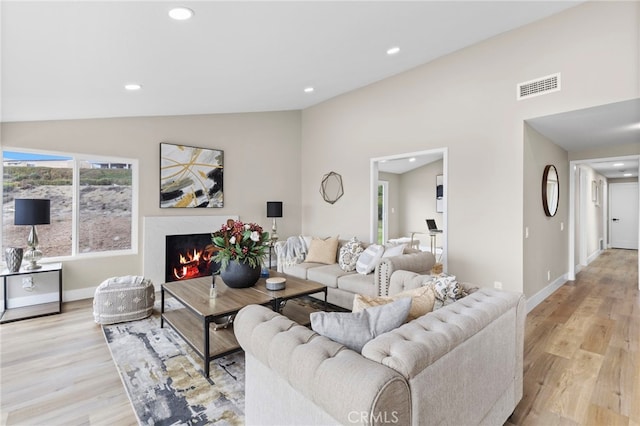 living room featuring lofted ceiling and light hardwood / wood-style floors