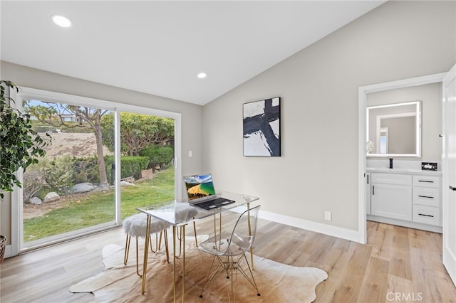 dining room featuring vaulted ceiling, sink, and light hardwood / wood-style floors