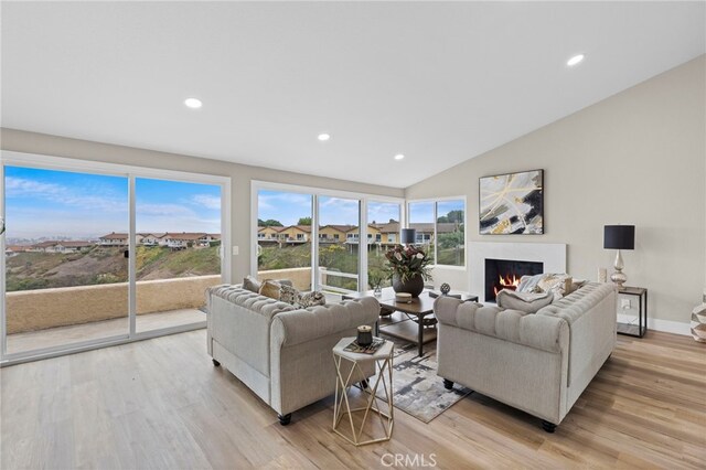 31002 Flying Cloud Dr, Laguna Niguel, CA 92677 - living room with a warm lit fireplace, light wood-style floors, recessed lighting, and lofted ceiling