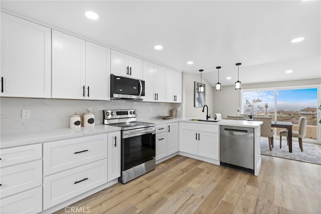 kitchen with pendant lighting, sink, stainless steel appliances, white cabinets, and kitchen peninsula